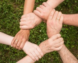 Hände von Menschen verschiedener Altersgruppen die ineinandergreifen und einen Kreis bilden