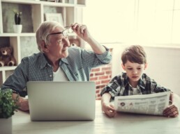 Generationen: Großvater am Laptop und Enkel mit der Tageszeitung