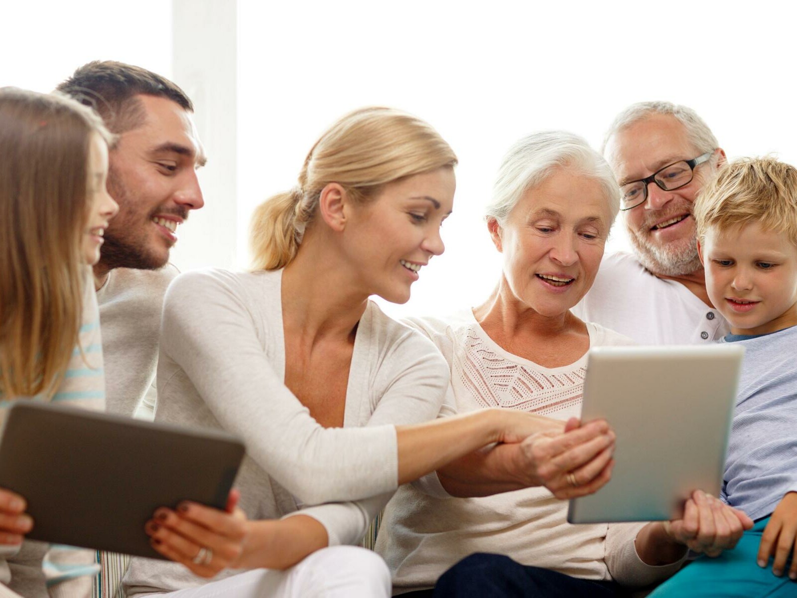 Drei Generationen: lächelnde Familie mit Tablet zu Hause auf dem Sofa
