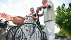 Ältere Dame und älterer Herr mit Fahrrädern