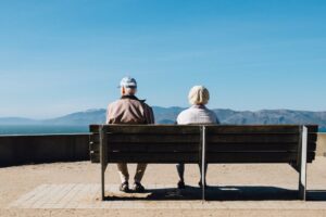Eine ältere Frau und ein älterer Mann sitzen auf einer Bank.