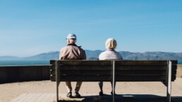Eine ältere Frau und ein älterer Mann sitzen auf einer Bank.