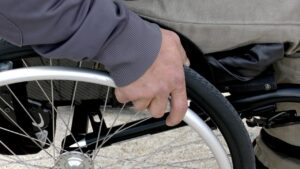 Person im Rollstuhl mit einer Hand am Rad.