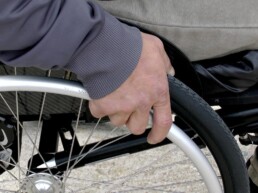 Person im Rollstuhl mit einer Hand am Rad.