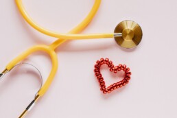Ein Herz und ein Stethoskop auf pinkem Grund.