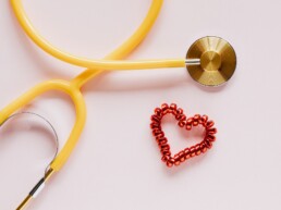 Ein Herz und ein Stethoskop auf pinkem Grund.