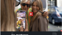 Eine Frau fotografiert zwei ältere Frauen auf der Straße mit einem Smartphone.
