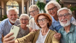 Fröhliche Gruppe von Senioren haben Spaß bei der Aufnahme von Selfies in der Seniorenwohnanlage mit modernem Smartphone