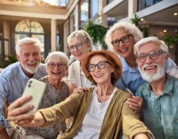 Fröhliche Gruppe von Senioren haben Spaß bei der Aufnahme von Selfies in der Seniorenwohnanlage mit modernem Smartphone