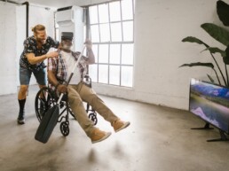 Mann im Rollstuhl mit Paddel in der Hand und VR-Brille erlebt virtuelle Bootfahrt